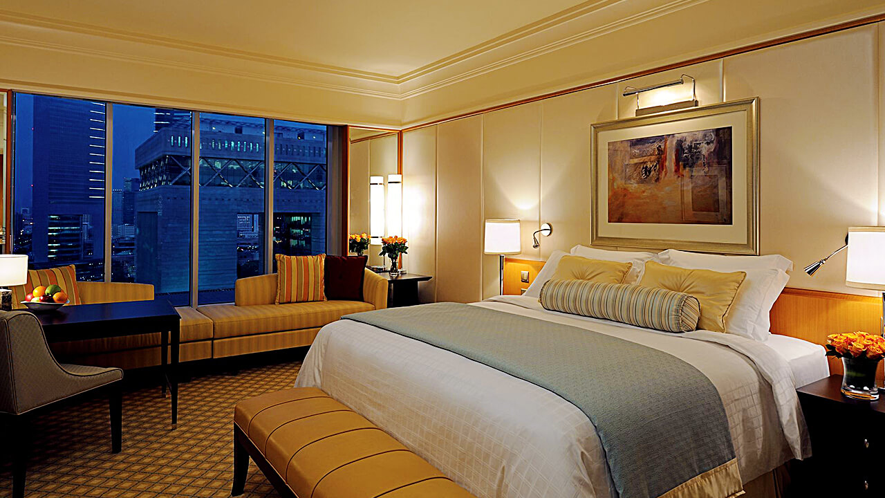 Guest room with a king bed windows overlooking the city at night