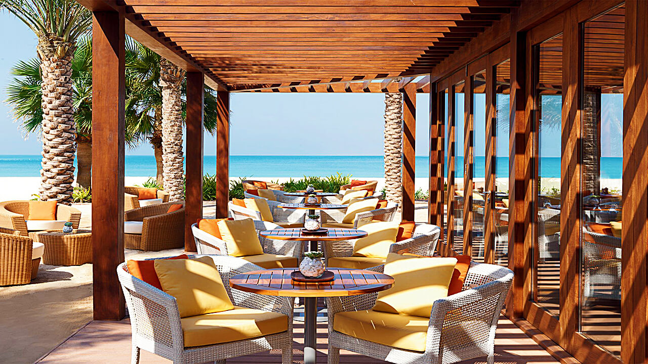 Patio seating shaded by a viga ceiling and with views of the ocean